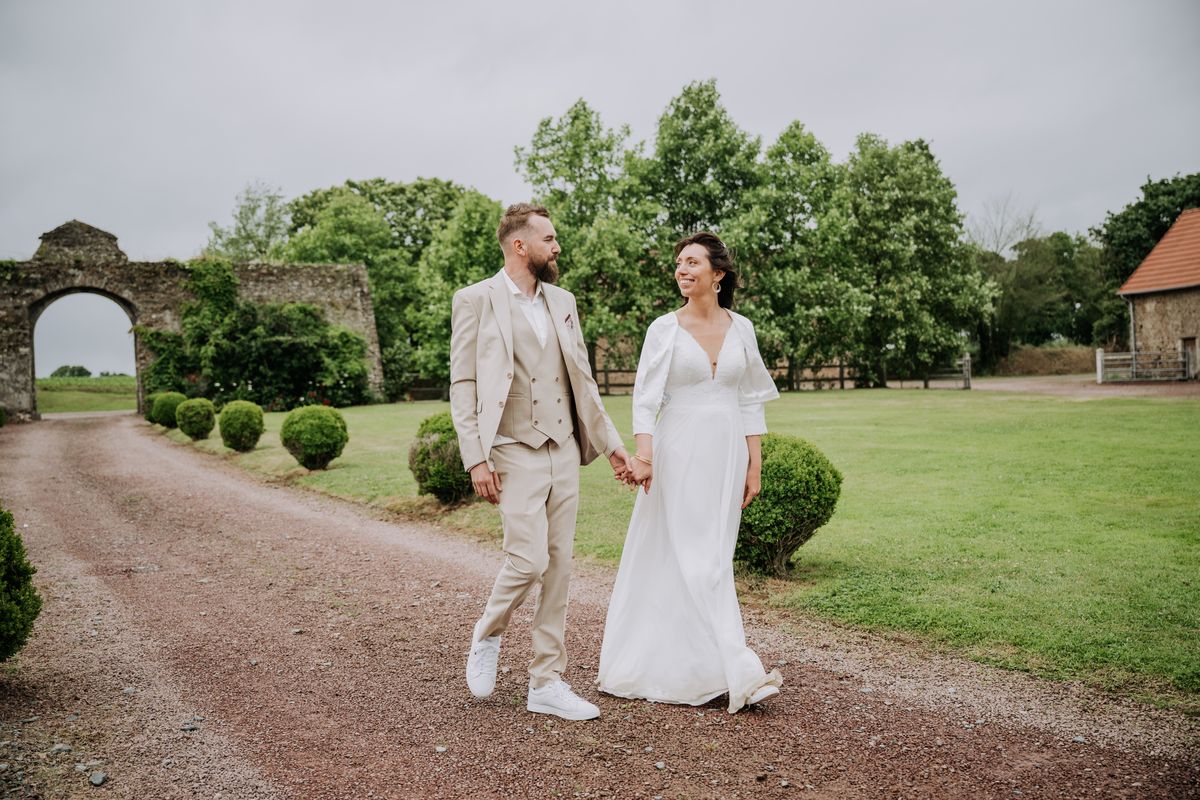 Manuella et Christopher marchent main dans la main dans l'allée d'un château