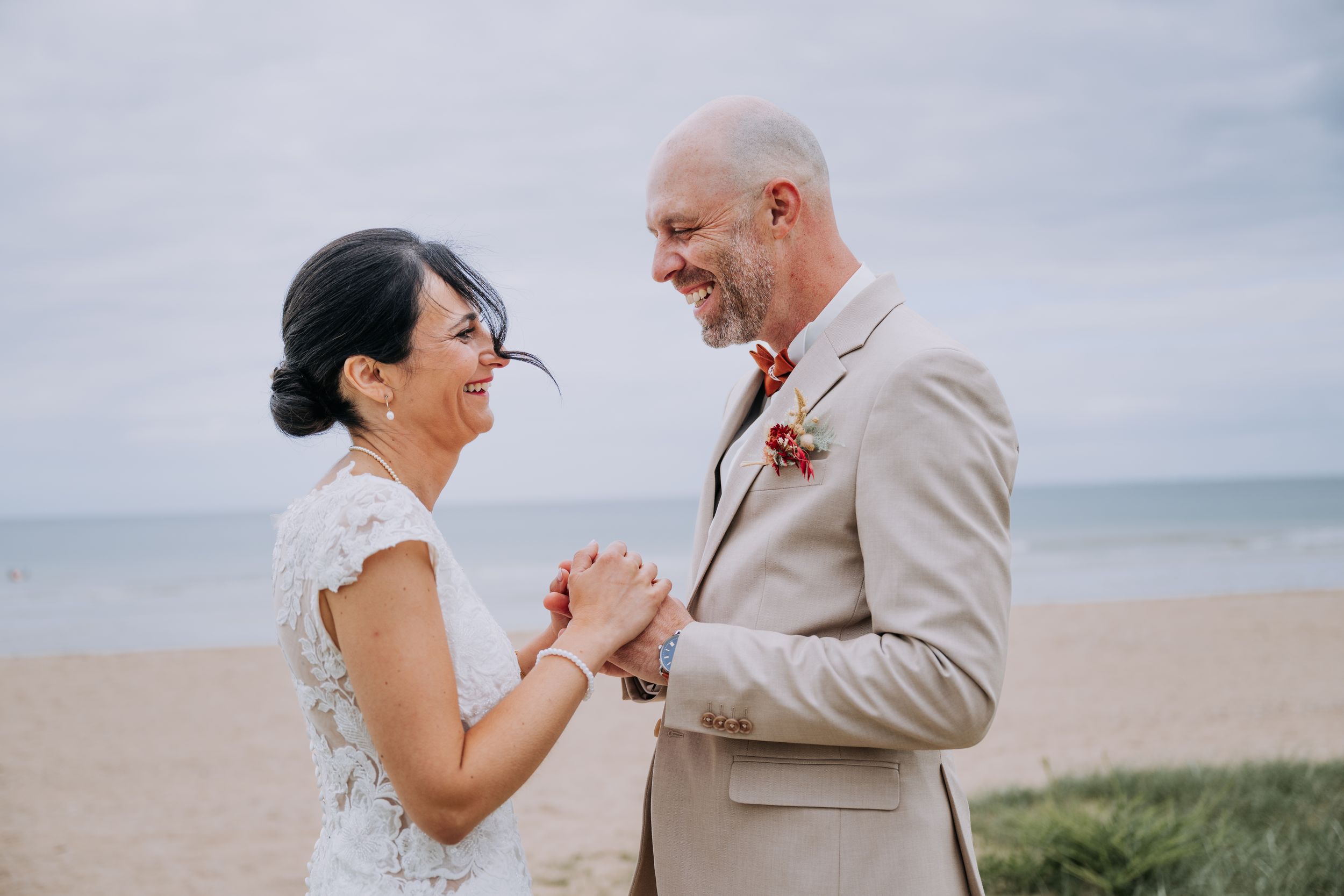 Teresa et Julien rient ensemble, mains jointes, sur une plage normande